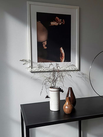 siyah metal masa, dekoratif vazolar, çerçeveli sanat, doğal ışık, minimalist tasarım, duvar resmi, iç dekor, modern mobilya, ev dekorasyonu, duvarda sanat, kurutulmuş çiçekler