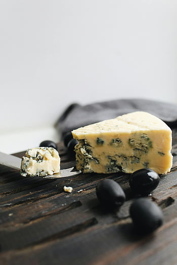 blue cheese, close-up photo, wooden board, black olives, gourmet presentation, cheese slice, cheese knife, food photography, cheese garnish, cheese platter, cheese appetizer