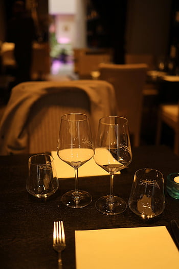 restaurant table, empty glasses, refined arrangement, upscale restaurant, table setting, cutlery, dining experience, elegant atmosphere, glassware, fine dining, ambient lighting