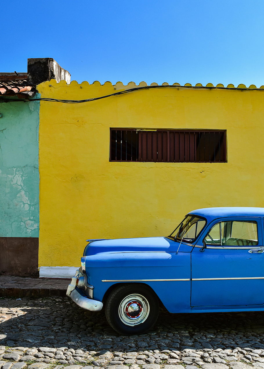 Historické auto, modré auto, žluté zdi, klasické auto, trinidad, kuba, barevné zdi, slunečný den, živý městský život, dlážděné ulice, historické vozidlo