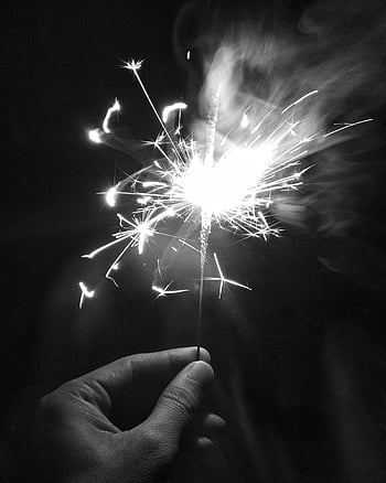 monochrome photo, person holding sparkler, close-up hand, sparkler, vibrant celebration, illuminating darkness, black and white, night celebration, festive moment, sparkler light, celebration sparkler