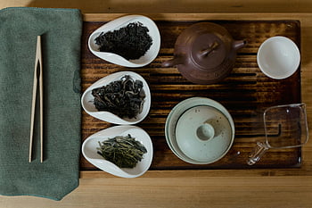 Asian tea ceremony, traditional tea setup, tea cups, teapots, tea leaves, chopsticks, ceramic bowls, wooden tray, artistic setup, tea presentation, tea culture
