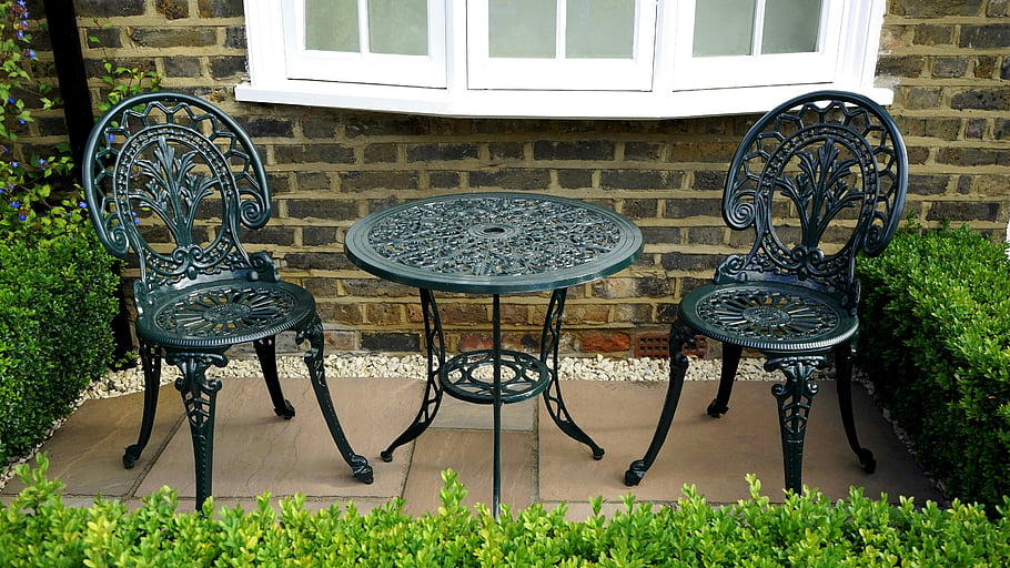 black steel table, vintage iron chairs, elegant outdoor garden, brick wall setting, patio furniture, outdoor dining set, garden decor, vintage table and chairs, outdoor iron furniture, garden table, garden chairs