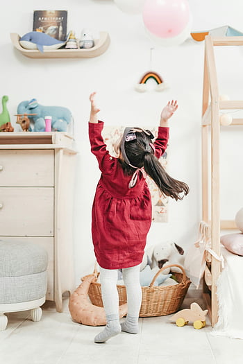 in abito rosso, catturare palloncini, Camera da letto accogliente, struttura del letto in legno bianco, ragazza che gioca, camicia rossa a maniche lunghe, Scena giocosa, sala giochi al coperto, La stanza dei bambini, animali imbalsamati, Decorazione arcobaleno