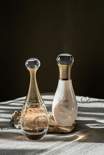 Dior J'adore, parfüm palackok, Minimalista csendélet, elegáns design, táblázat beállítása, luxus illat, Dior márka, üveg palackok, fehér üveg, arany díszítés, parfüm kijelző