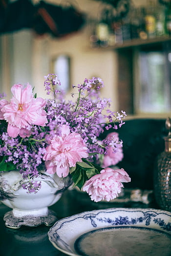 růžové pivoňky, Vintage váza, okrasná deska, Vnitřní nastavení, Okouzlující květiny, klidná atmosféra, Elegantní výzdoba, uspořádání stolu, květinové kytice, fialové květy, dekorativní talíř