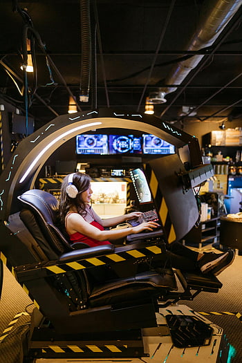 コンピューターゲームをプレイする女性、 モダンなゲーミングチェア、 ハイテクゲーム体験、 屋内ゲームのセットアップ、 没入型ゲーム、 ゲーミングヘッドセット、 未来的なゲームステーション、 アーケードゲーム、 インタラクティブなゲーム、 バーチャルリアリティゲーム、 ゲーム環境