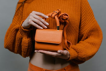 Mini oranžová kožená taška, pletený svetr, Žena drží kabelku, Nastavení studia, Oranžová kabelka, oranžový svetr, Mini kabelka, kožená taška, foto studio, Oranžová móda, žena móda