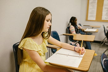 Mädchen studieren, Klassenzimmer, Notizen schreiben, Notizbuch, junges Mädchen, Schreibtisch, allein, fokussiert, Schule, Bildung, gelbes Kleid