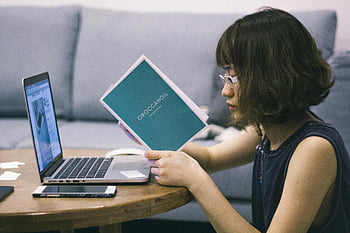 Aziatische vrouw, Zwart mouwloos shirt, bruine tafel, laptop, document, Serene werkruimte, gericht werk, Marokkaansoil, toevallige setting, thuiskantoor, bril