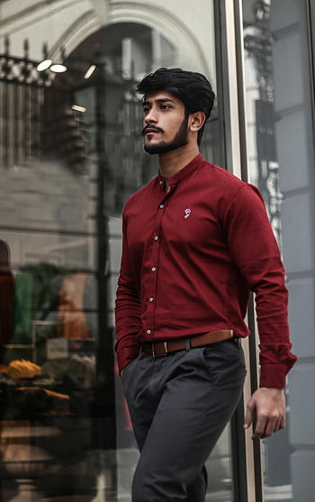 man in red dress shirt, stylish urban outfit, walking confidently, city street photoshoot, handsome young man, outdoor photoshoot, near wall, confident walk, urban fashion, city fashion, red shirt outfit
