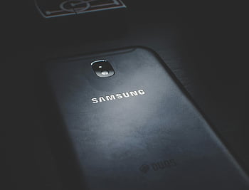 black Samsung phone, close-up photo, smartphone, dark wooden surface, detailed view, logo, Samsung logo, mobile phone, technology, device, electronics