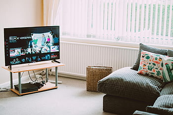 Flatscreen slimme televisie, moderne bank, decoratieve kussens, Streaming shows, chique woonkamer, comfortabele woonkamer, Smart TV, Populaire shows, woonkamer decor, moderne inrichting, Netflix streaming