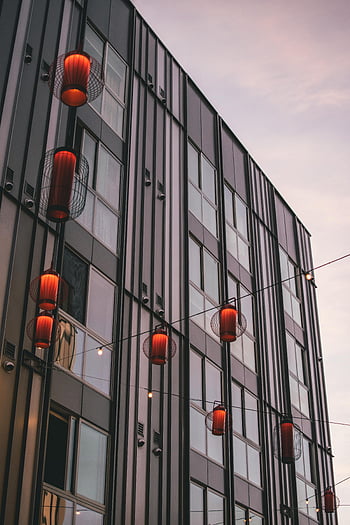 low angle photography, curtain wall building, contemporary building exterior, hanging red lanterns, dusk, modern architecture, urban scene, exterior design, architectural photography, evening lighting, building facade