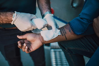 first aid, healthcare professional, white bandage, injured arm, medical gloves, bandage application, left hand, tattooed arm, emergency care, medical assistance, healthcare worker