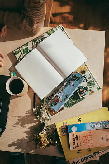 woman at table, empty planner, coffee, cozy workspace, open notebook, sunlit table, flat lay, books, workspace setup, productivity, planning