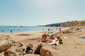 zomerstrand, Mensen genieten van zon, zee, rustig strand, zandstrand, parasols, beachgoers, uitzicht over de oceaan, kustlandschap, zonnige dag, strandpicknick