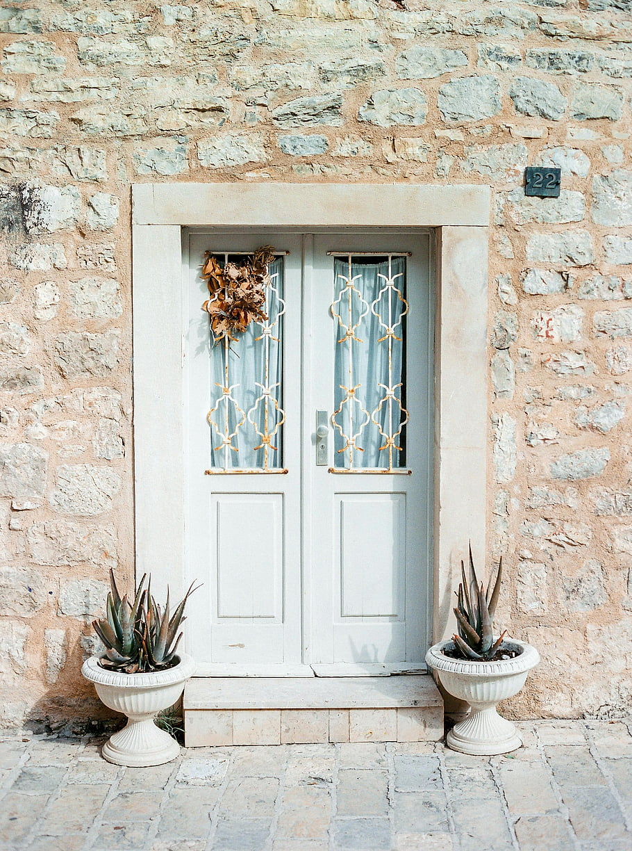white wooden doors, old house facade, potted plants, vintage stone facade, decorative white door, elegant vintage, stone wall, white door, potted cacti, rustic house, old house entrance