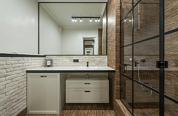 modernes Badezimmer, stilvoller Spiegel, freiliegende Ziegelmauer, Schlanke Glasdusche, elegantes Badezimmerdesign, Innenarchitektur, Badrenovierung, Badezimmer Dekor, Badezimmereitelkeit, Glasduschkabine