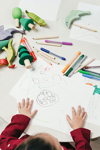 child drawing, colored pencils, wooden toys, white table, creative drawing, kid painting, art supplies, children's art, drawing activity, playtime, educational toys