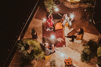 vista aerea, persone sedute, godersi la musica, impostazione accogliente, scena notturna, Raccolta di gruppo, Evento indoor, strumenti musicali, illuminazione calda, piante, Atmosfera intima