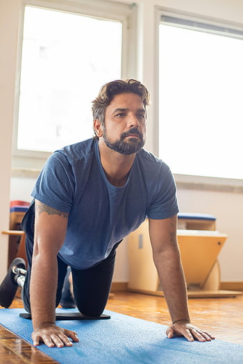 uomo che si esercita, camicia blu, gamba protesica, tappetino yoga, pilates, stanza luminosa, uomo determinato, fitness, allenarsi, Esercizio interno, Salute