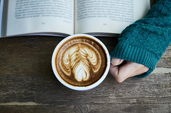 cappuccino, latte, taiteellinen vaahto, avoin kirja, puinen pöytä, kodikas hetki, kahvikuppi, latte art, lämmin juoma, lukeminen, kahviaika