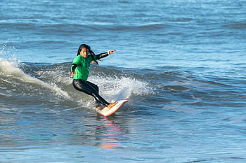 Frau Surfen, Meer, sonniger Tag, Wassersport, qualifizierter Surfer, Ozean Wellen, Surfbrett, Surferin, Strandaktivität, Outdoor-Abenteuer, aktiver Lebensstil