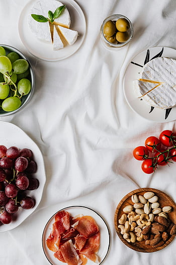 formaggio con foglie di basilico, spuntini gourmet, distesa piatta, tessuto bianco, formaggio, uva, noccioline, pomodori, presentazione elegante, fotografia di cibo, Tagliere di salumi