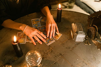 fortune teller, tarot cards, candles, mystical setting, indoor setting, hands touching, card reading, crystal ball, ornate box, divination, spiritual practice