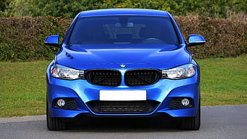 blue BMW sedan, green lawn grass, rural road, front view, stylish car, outdoor parking, blue car, BMW grille, car headlights, car exterior, sedan vehicle