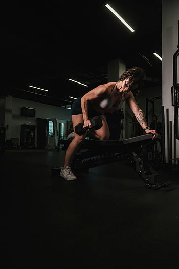 Frau hebt Hantel, Fitnesstraining, Krafttraining, Fitness, Frau ausüben, Hanteln, Trainingsroutine, Fitnessumgebung, Fitness Motivation, gesunder Lebensstil, Trainingsgeräte