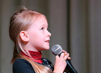 girl holding microphone, cute young girl, singing on stage, black dynamic microphone, close-up profile view, passionate singing, stage performance