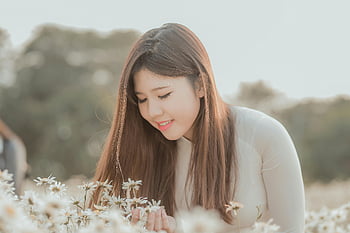 Frau, die weiße Gänseblümchen hält, Selektive Fokusfotografie, junge Frau, Gebiet der weißen Gänseblümchen, leise lächeln, Porträt im Freien, Naturfotografie, Blumenfeld, Gelassener Moment, Weicher Fokus, natürliche Schönheit