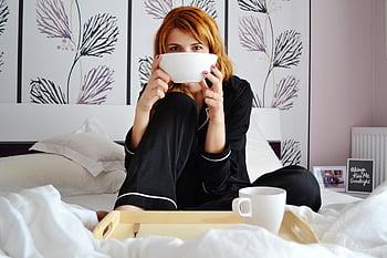 woman in pajamas, sitting on bed, holding bowl, cozy bedroom, cup of coffee, stylish bedroom, relaxation, morning routine, comfortable bed, breakfast in bed, cozy morning