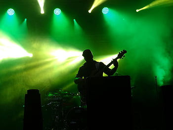 mann spiller gitar, sceneprestasjon, levende grønne lys, Dynamisk atmosfære, Silhouette gitarist, levende musikk, konsert scenen, scene belysning, musikalsk ytelse, Grønt scenelys, live performance