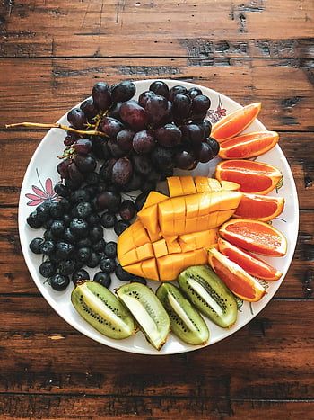 assorted fruits, ceramic plate, grapes, mango, kiwi, oranges, fruit platter, wooden table, colorful fruits, blueberries, fruit arrangement