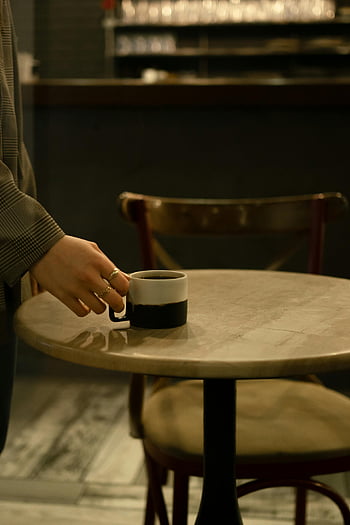 donna che beve caffè, latte, bar, Scena calda, mano che appoggia la tazza di caffè, tavolo di legno, Atmosfera accogliente, caffetteria, impostazione interna, momento casuale, anelli