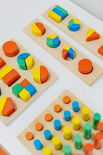 colorful shapes, wooden toys, preschool learning, playroom decor, vibrant toys, close-up shot, white table, educational toys, children's toys, shape sorting, colorful blocks