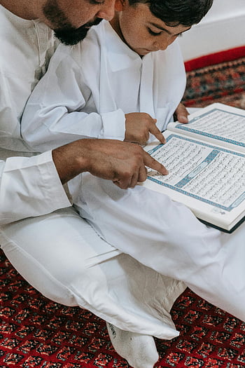 padre e figlio, leggere il Corano, fede e tradizione, Famiglia islamica, studio religioso, Legame padre-figlio, Lettura del Corano, connessione spirituale, valori tradizionali, abbigliamento bianco, pavimento in moquette
