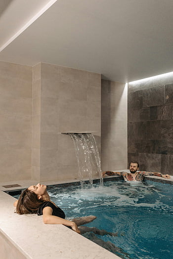 woman in swimming pool, modern indoor pool, couple relaxing, indoor pool, relaxing moment, modern pool, indoor swimming pool, couple in pool, pool waterfall, spa pool, relaxation in pool