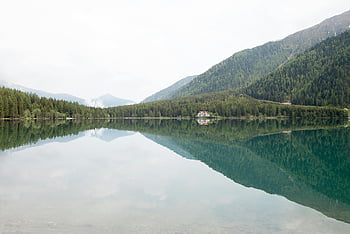 calm body of water, mountain ranges, tranquil mountain lake, reflecting trees, reflecting sky, nature lovers, serene landscape, peaceful scenery, mountain reflection, lake reflection, natural beauty