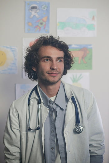 dětský lékař, Bílé knoflíkové tričko, stetoskop, dětská umělecká díla, Světlá kancelář, Usmívající se doktor, Lékař, zdravotnický pracovník, Prostředí přátelské k dětem, lékařský kabát, Nastavení zdravotní péče