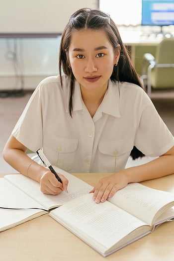 woman in white polo, writing notebook, focused young woman, library setting, education symbol, study focus, academic environment, learning process, dedicated student, educational pursuit, notebook writing