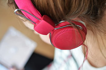 pink headphones, woman wearing headphones, close-up shot, vibrant red headphones, focused on music, music listening, audio device, earphones, personal audio, listening experience, red earphones