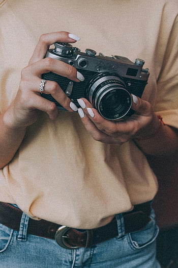 mujer sin rostro, camara vintage, tomando fotos, mujer joven, atuendo casual, fotografía de interior, fotografía de época, Cámara fotográfica, Estilo casual, entorno interior, afición a la fotografía
