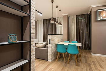 sala da pranzo, sedie turchesi, design contemporaneo, Area abitativa accogliente, tavolo vicino al divano, interni eleganti, arredamento moderno, soggiorno, pavimento di legno, luci a sospensione, muro di mattoni