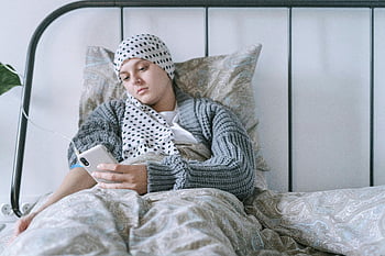 zieke vrouw, hoofddoek, smartphone, liggend in bed, intraveneuze lijn, hoop, herstel, bedlegerig, geduldig, gezondheidszorg, herstelreis