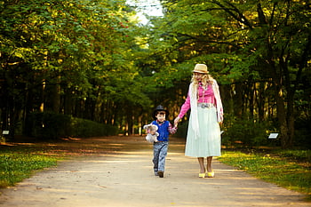 woman walking with boy, cheerful mother and son, sunlit park, embracing nature, togetherness, outdoor walk, family bonding, sunny day, nature walk, park scene, mother and child