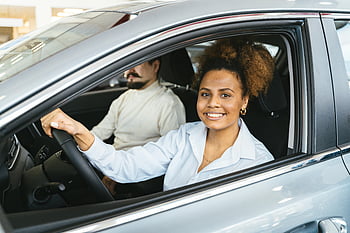 African American woman, smiling woman, test driving, new car, dealership, joyful expression, sitting inside car, car interior, car showroom, vehicle, driver